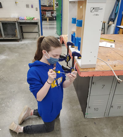 Female student using Realityworks' Electrical Wiring Kit