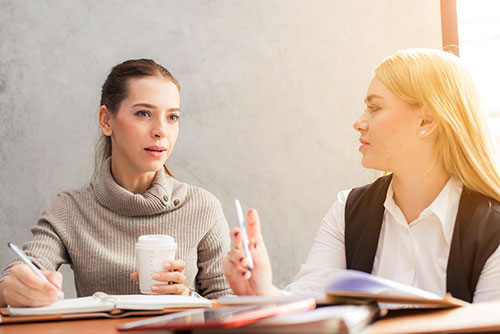 Women conversing over notebooks