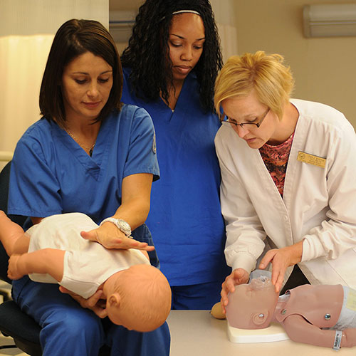 Nurses and doctor using infant choking and CPR trainers