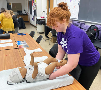 Student changing the diaper of a CCE Program Baby