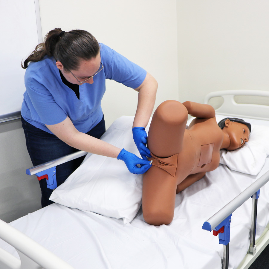 Student inserts a simulated suppository rectally into the Medication Administration Trainer