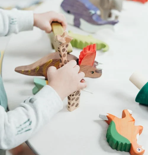 Close up of child's hands playing with block dinosaurs