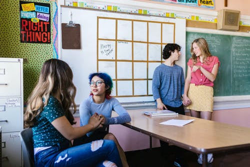 Two pairs of middle school students talking to each other in a classroom
